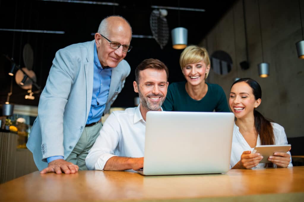 A group of coworkers gather around a computer at a cafe