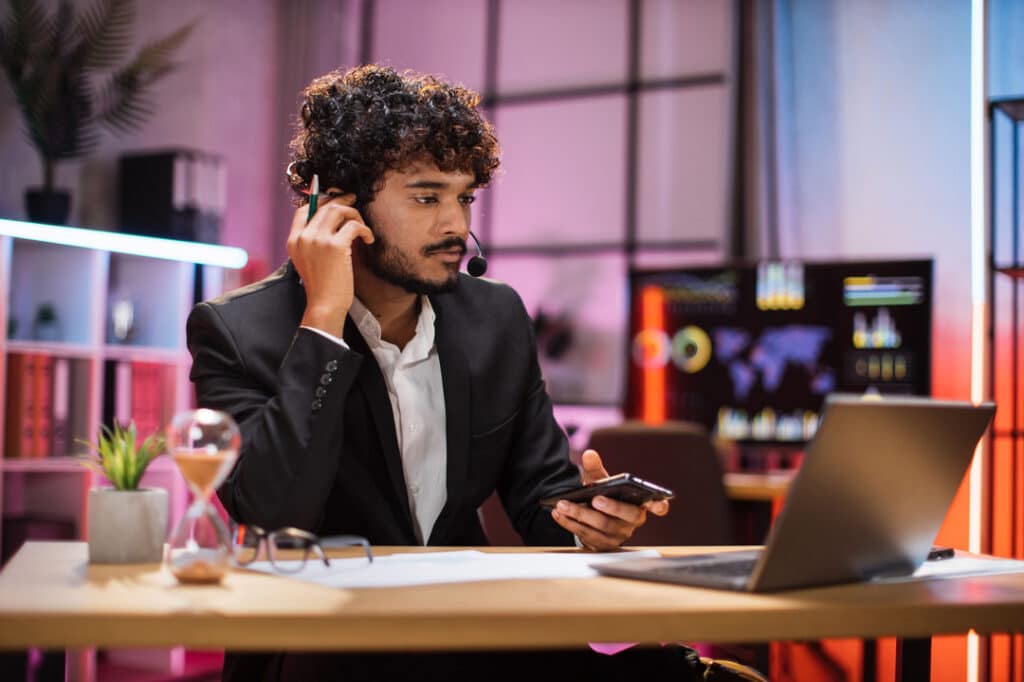 Man takes a call at his desk in the evening